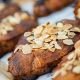 Shallow depth of field shot highlighting the delicate almond flakes atop freshly baked croissants. The warm tones and careful composition emphasize the artisanal quality of these breakfast pastries.