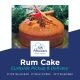Traditional rum-soaked cake adorned with star anise, cinnamon, and candied cherry. The warm lighting emphasizes the moist, golden crumb and festive spice garnish.
