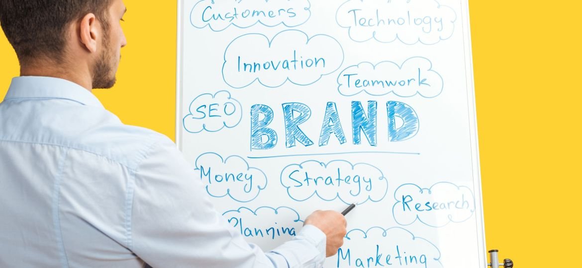 back view of businessman standing near white office board, pointing at words on flipchart