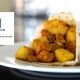 Artful presentation of The Harbor Club's signature curry roti, featuring tender curried chicken and potatoes wrapped in traditional flatbread. The shallow depth of field emphasizes the rich, golden spices.