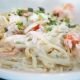 Creamy fettuccine alfredo with perfectly sautéed jumbo shrimp, garnished with fresh herbs. The close-up capture highlights the silky texture of the sauce and the delicate pink of the seafood.